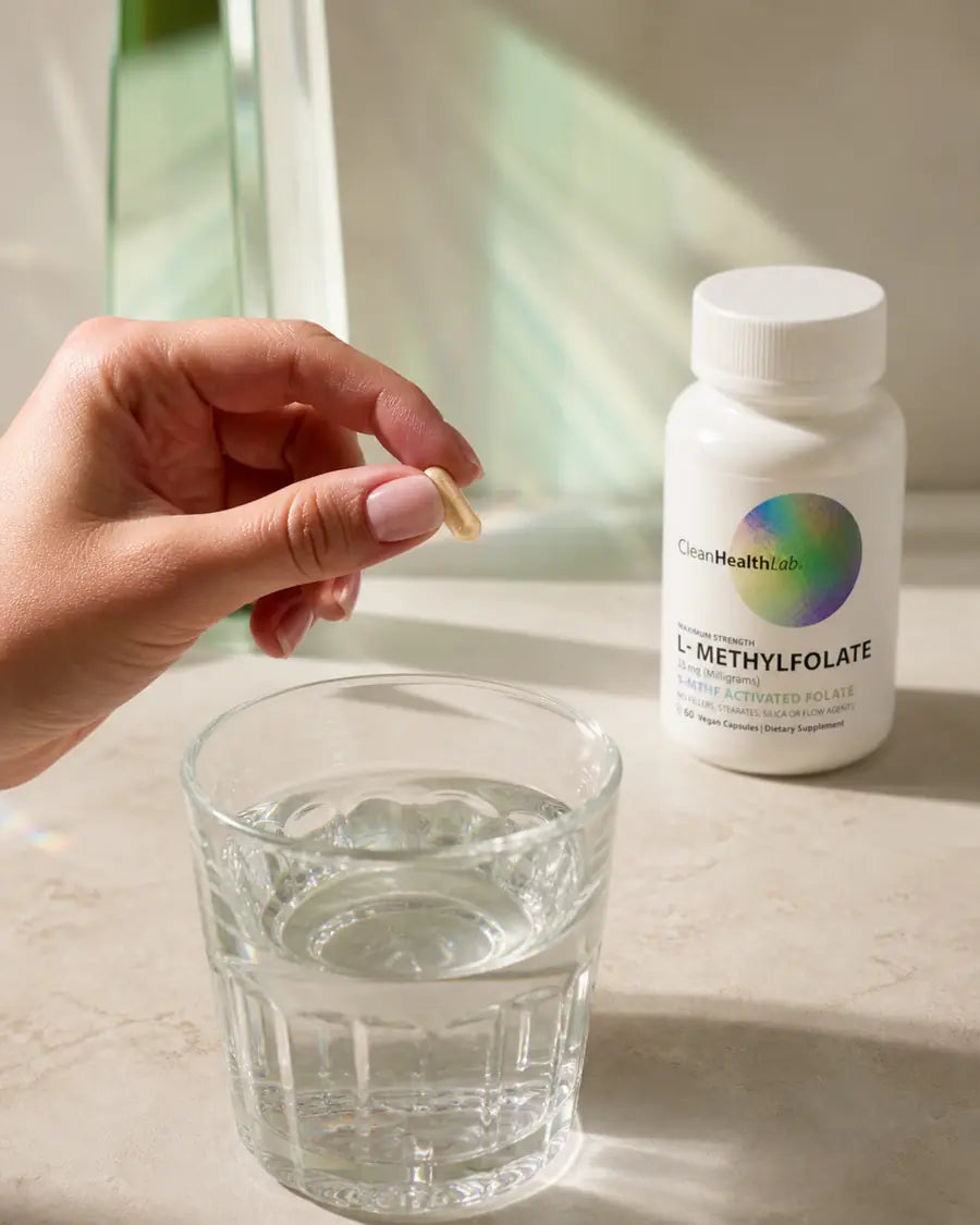 Natural environmental portrait of an adult holding one small warm-beige size number 2 capsule at human scale in a calm morning kitchen, with the compact bottle softly out of focus behind